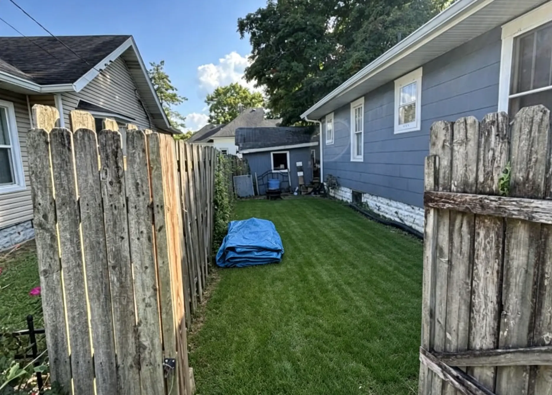 After: the same side yard cleared of overgrowth with a mowed, usable lawn