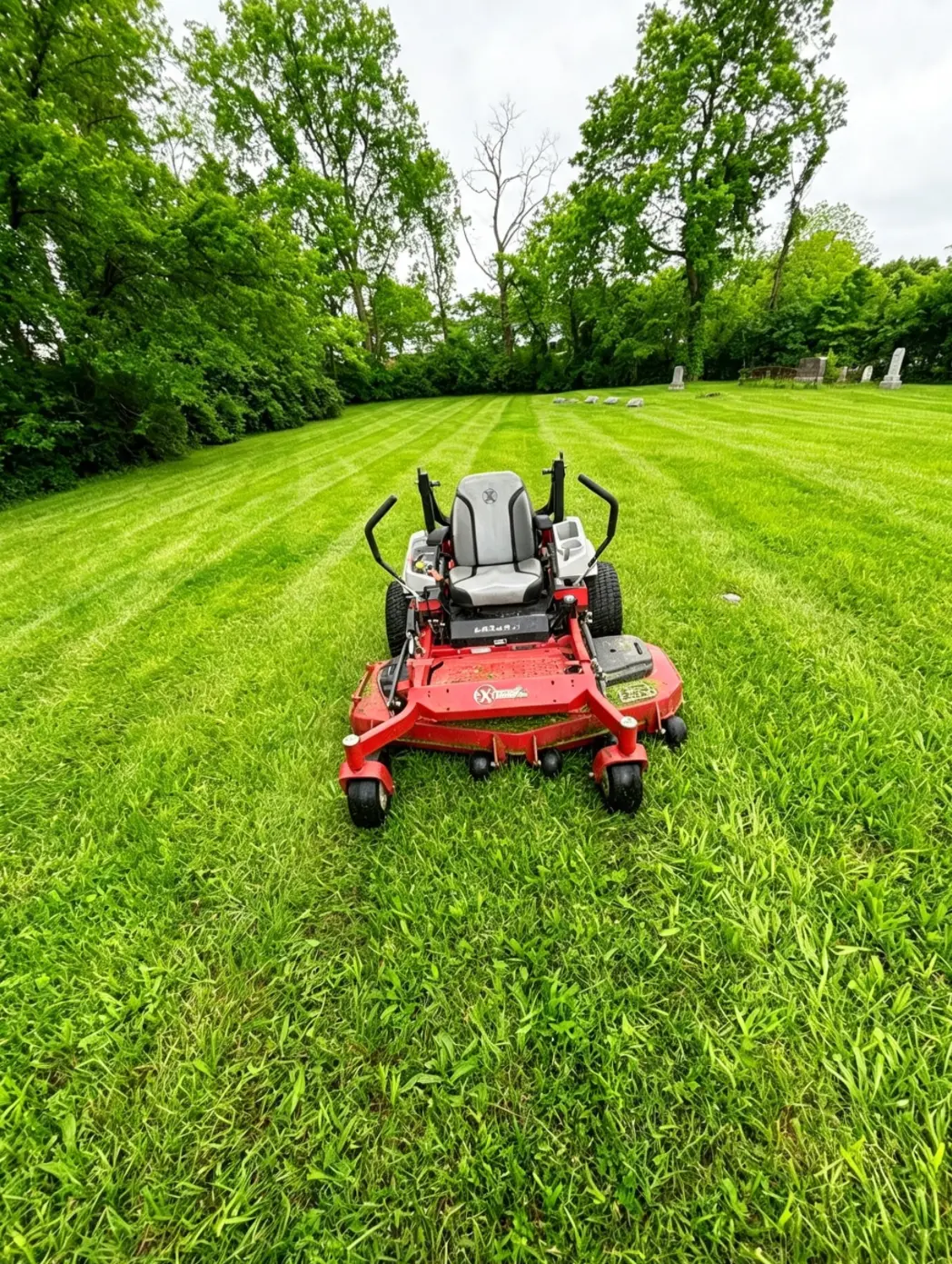 Zero-turn mower on a large striped grass property maintained by Emberton Landscapes