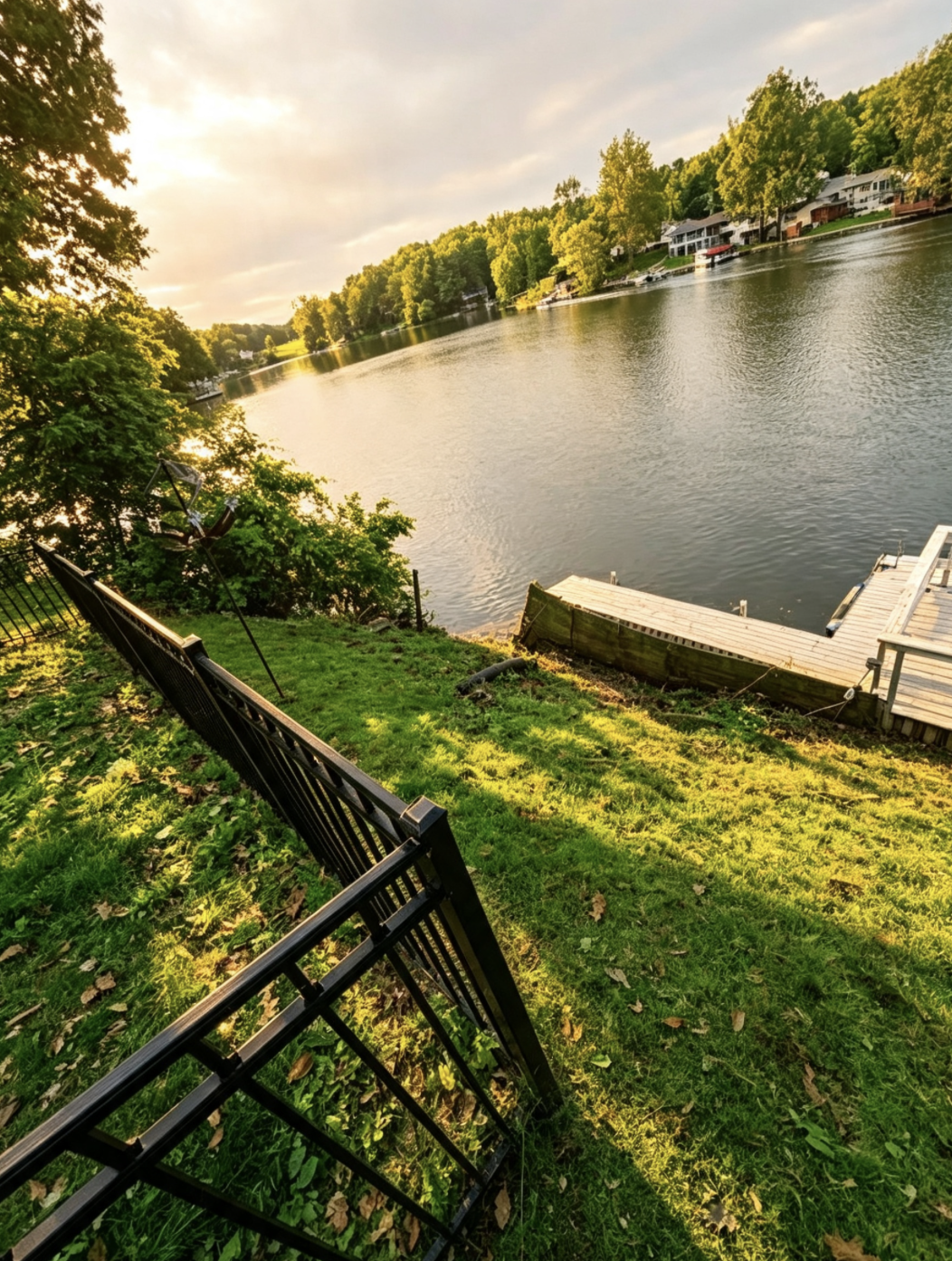 Cleared lakeside lawn and shoreline with a dock at golden hour after brush removal